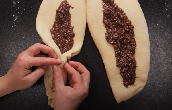 Ένα κίτρινο βύσμα ζύμης γεμάτο nutella και αμύγδαλα